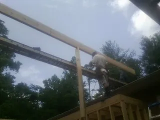 Carpenter setting a ridge beam over a new addition frame — Ice Dam Removal by Roofing Brothers in Boothbay