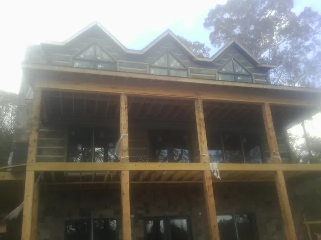 Dormers and porch framing on a large log home under construction — Roof Coating work by our crew in Boothbay
