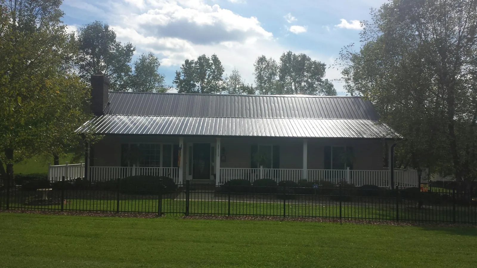 Gray metal roof on a brick ranch with a full width front porch — Gutter Guard Installation work by our crew in Boothbay
