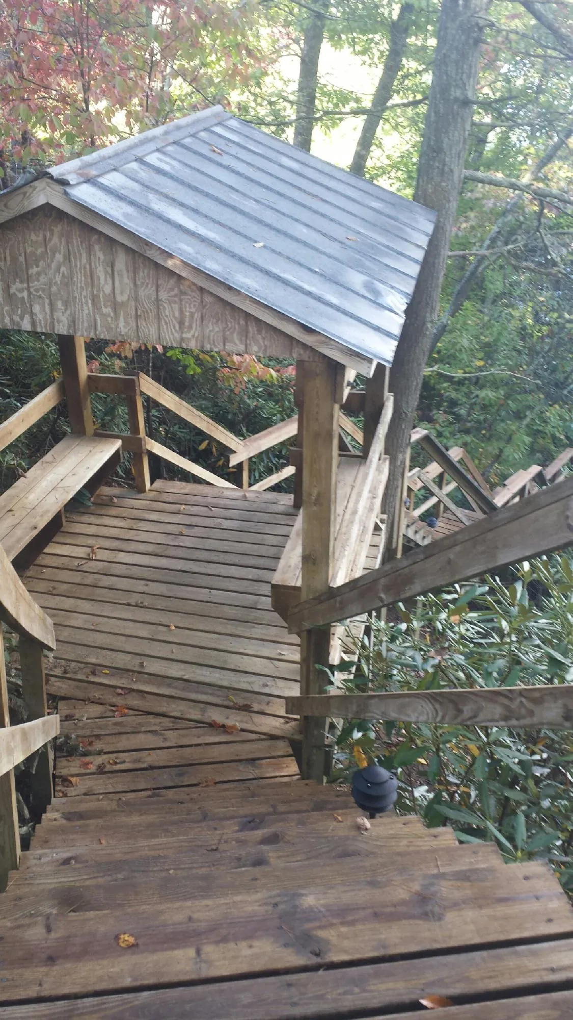 Metal roofed shelter over wooden steps on a wooded walkway — Skylight Repair & Installation work by our crew in Boothbay
